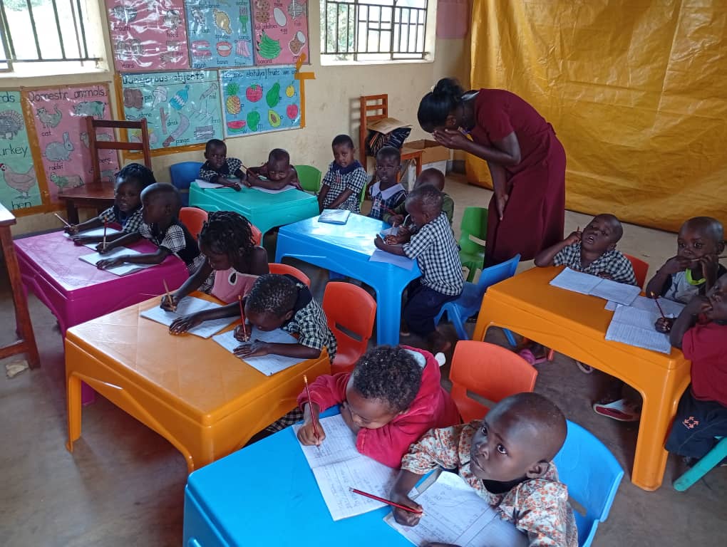 A teacher helping young pupils with their writing at St. Mary's